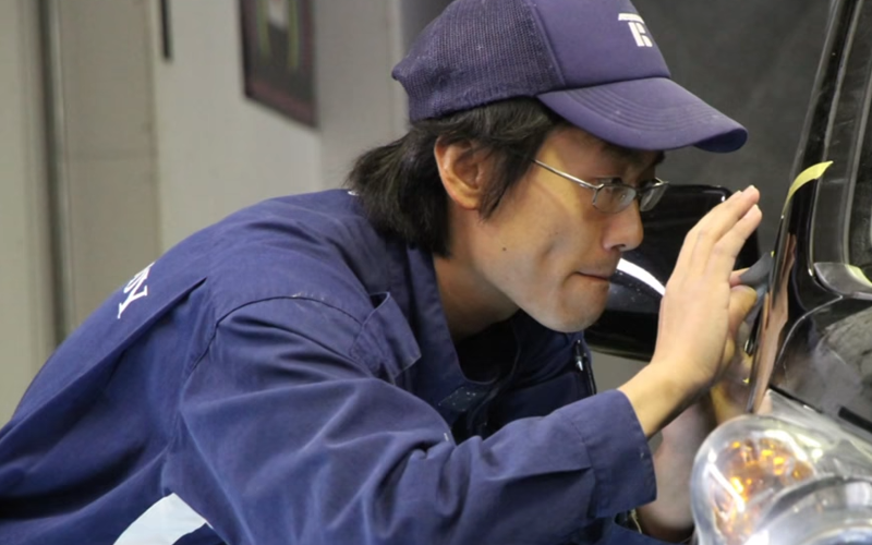 塗装面を間近で確かめる職人