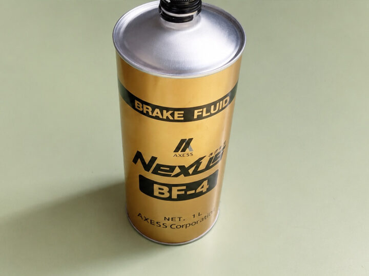 02 - 鈑金塗装・カーコーティング・車検|山口県周南市 東洋ボデー株式会社 Gold metal can labeled 'BRAKE FLUID' with 'Nexus BF-4' branding on a pale green surface, showing a screw-top opening.